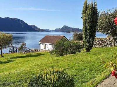 a house on a lawn next to a body of water at Family Oasis with Lake View-By Traum in Ålesund