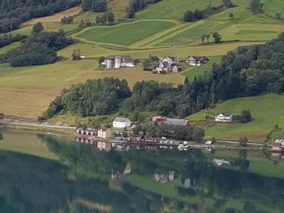 a reflection of a farm in a body of water at Nesset Fjordcamping in Olden
