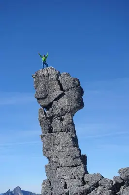 a man standing on top of a rock formation at Romsdalseggen Lodge in Isfjorden
