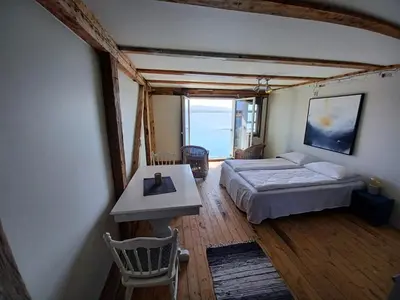 a bedroom with a bed and a table and a window at Sveggvika Guesthouse in Averoy