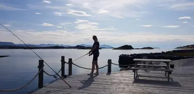 a woman is standing on a dock with a rope at Sveggvika Guesthouse in Averoy