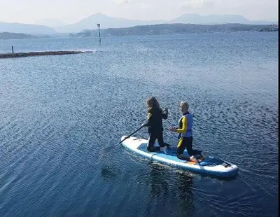 two people on a paddle board in the water at Sveggvika Guesthouse in Averoy