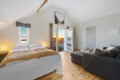 a bedroom with a bed and a couch at Sveggvika Guesthouse in Averoy