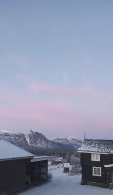 a house in the snow with mountains in the background at Eikre Fjellgård in Hemsedal