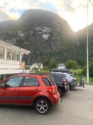 a row of parked cars in front of a mountain at Eidfjord Hytter in Eidfjord
