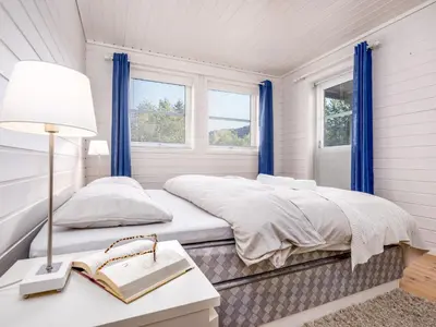 a bedroom with a bed and a table with a lamp at Holiday Home Sjøbuvågen by Interhome in Korssund