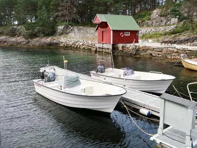 two boats are docked at a dock with a red house at Holiday Home Nesholmen by Interhome in Leirvik