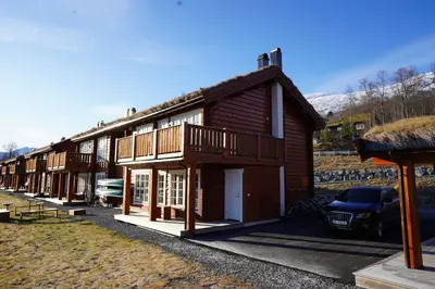 a wooden house with a car parked in front of it at Lake View Apartment 2 bedrooms and loft in Stranda