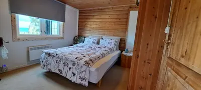 a bedroom with a bed with a wooden wall at Ønskedrømmen hytteutleie in Brandbu