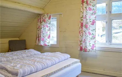 a bed in a room with two windows at Solvang in Hebnes