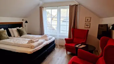 a bedroom with a bed and a red chair at Store Ringheim Hotel og Restaurant in Vossevangen