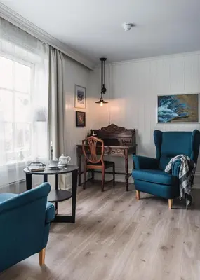 a living room with blue chairs and a table and a piano at Store Ringheim Hotel og Restaurant in Vossevangen