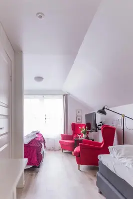 a white room with red chairs and a bed and a room at Store Ringheim Hotel og Restaurant in Vossevangen