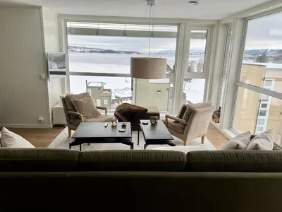 a living room with a couch and chairs and a large window at Moderne hytte in Gjøvik