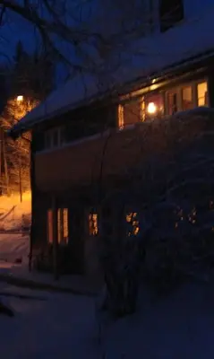 a house with lights on in the snow at night at Valdres Naturlegvis in Fagernes