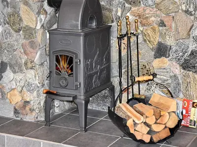 a wood stove with a pile of logs in front of a stone wall at Seaside Serenity in Settem Fjord-By Traum in Bø