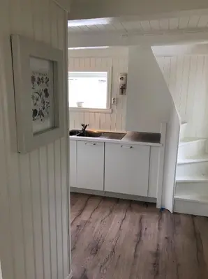 a kitchen with white cabinets and a sink and stairs at Pålberget in Råkvåg