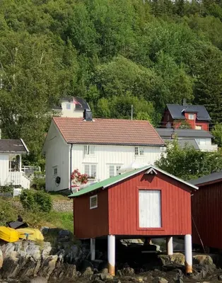 a red and white house and some houses and trees at Pålberget in Råkvåg