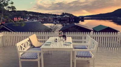 a white table and two chairs on a wooden deck at Pålberget in Råkvåg