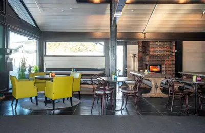 a restaurant with tables and chairs and a fireplace at Skeikampen Servicesenter in Svingvoll