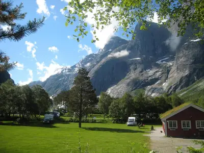 a view of a mountain with a house in a field at Trollveggen Camping in Åndalsnes