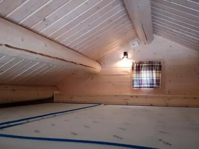 an attic room with a mattress in front of a window at Trollveggen Camping in Åndalsnes
