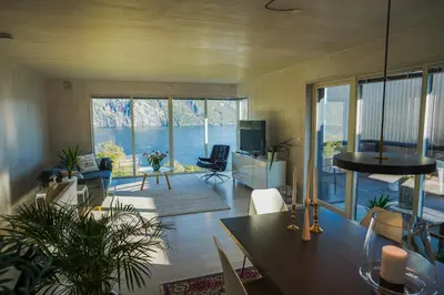 a living room with a table and a large window at Fjord View Apartment in Stranda