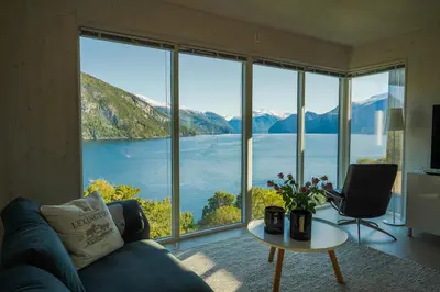 a living room with a large window view of a lake at Fjord View Apartment in Stranda
