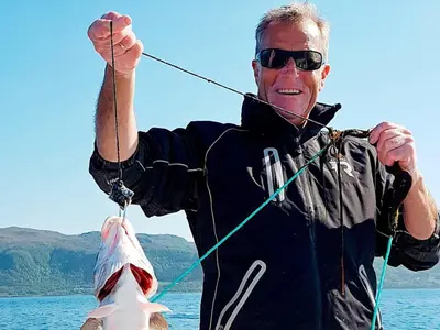 a man holding a fish on a fishing line at 10 person holiday home in Brattvåg in Brattvåg