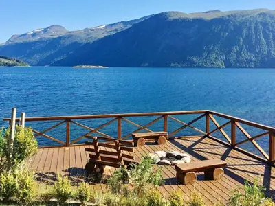 two benches sitting on a wooden deck near a body of water at 5 person holiday home in EIDSVÅG in Eidsvåg