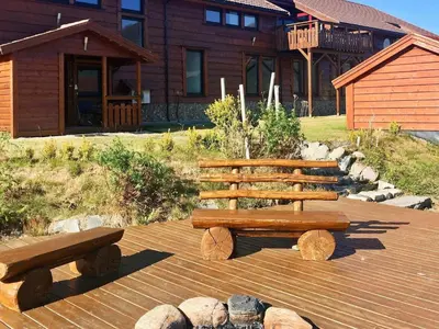 two wooden benches sitting on a deck in front of a house at 5 person holiday home in EIDSVÅG in Eidsvåg