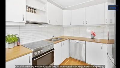 a white kitchen with white cabinets and a sink at Central apartment in walking distance from the city. in Ålesund