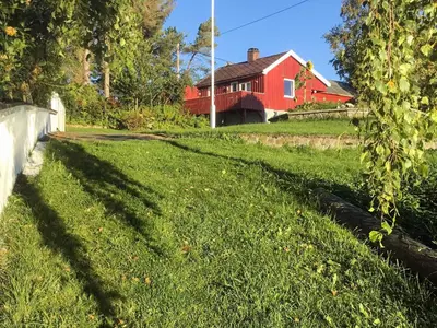 a red house with a grassy yard with a house at 6 person holiday home in averøy-By Traum in Averoy