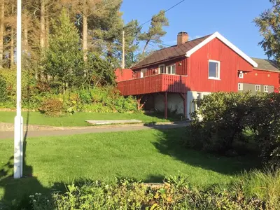 a red house with a porch on a lawn at 6 person holiday home in averøy-By Traum in Averoy