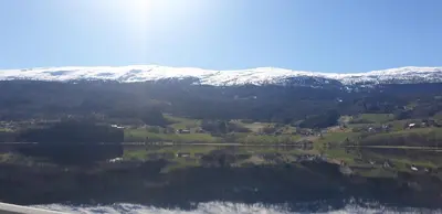 a reflection of snow covered mountains in a lake at New and Exclusive Cottage in Voss with a great view in Skulestadmo