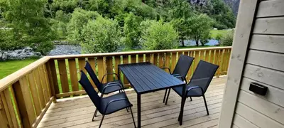 a table and chairs on a deck with a view of a river at Lunde Camping in Aurland