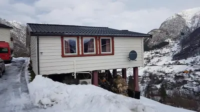 a small house in the snow next to a mountain at Leilighet 2240 in Haugsvær