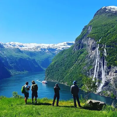 a group of people standing on a hill looking at a waterfall at Villa Lovise Riverside in Stranda