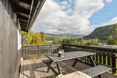 a wooden deck with a table and a bottle of wine at Topcamp Rustberg - Hafjell in Hafjell