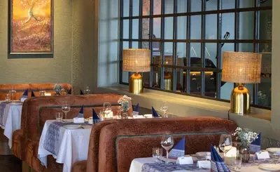 a dining room with two tables with chairs and windows at Savalen Fjellhotell & Spa in Tynset