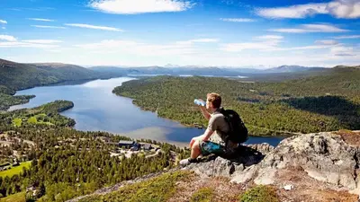 a man sitting on top of a mountain drinking a water bottle at Savalen Fjellhotell & Spa in Tynset