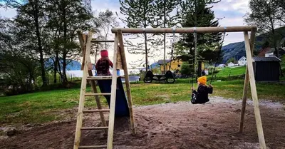 two children playing on a swing in a park at Sognhostel in Sørbø