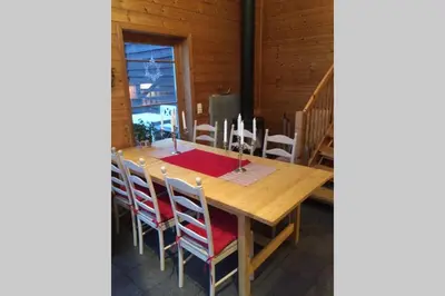 a wooden dining room table with chairs and a red table cloth at Skjerping gårdshus, in Lonevåg