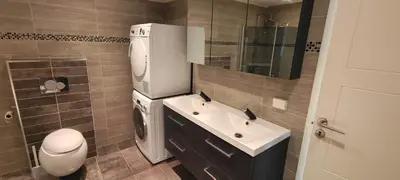 a bathroom with a sink and a washing machine at Lagunen Apartments in Bergen