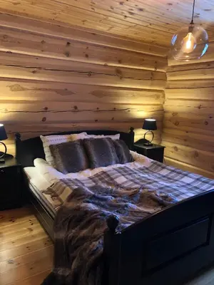 a bedroom with wooden walls and a bed with two lamps at Hyggelig laftehytte på 140kvm med Ski-In/Out in Uvdal