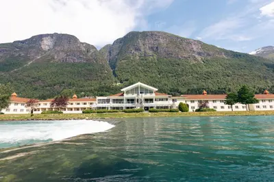 a resort on the water with mountains in the background at Hotel Loenfjord Loen in Loen