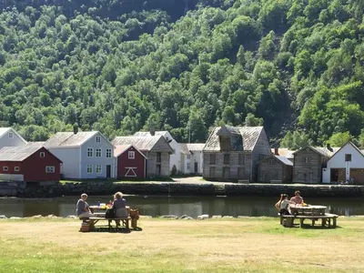 a group of people sitting at picnic tables by a body of water at Old town boutiqe apartments/ Gamle Lærdalsøyri boutique leiligheter in Lærdalsøyri