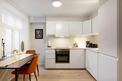 a kitchen with white cabinets and a table with chairs at Keyser Apartments 6 in Bergen