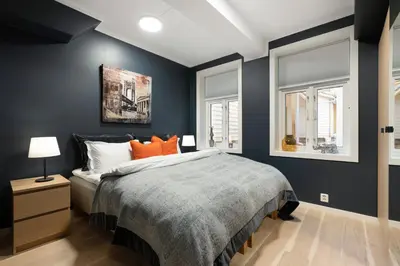 a bedroom with blue walls and a bed with orange pillows at Keyser Apartments 6 in Bergen