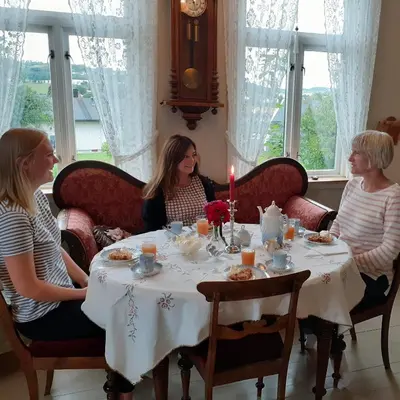 a group of women sitting around a table with a candle at Strømnes - Oldefars gjestehus Inderøy in Straumen